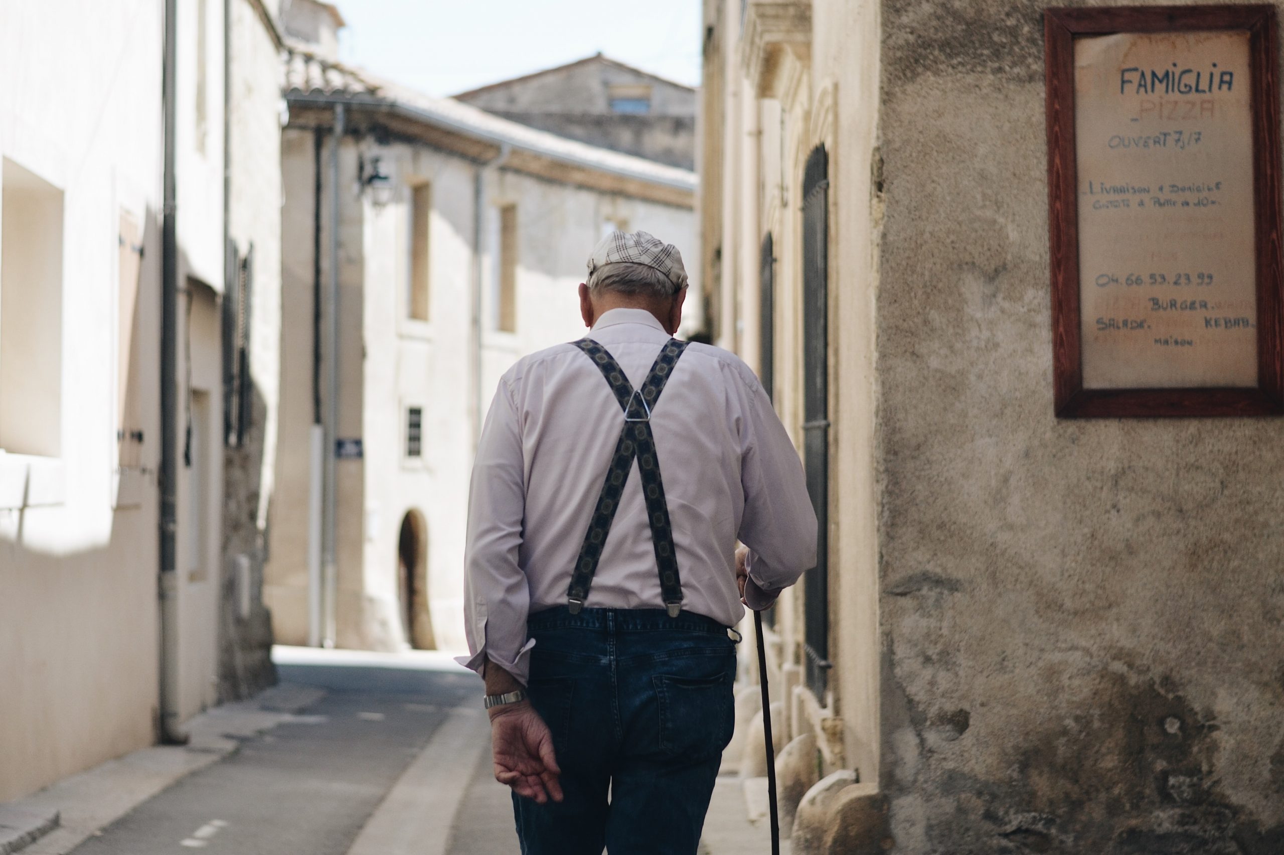 idős ember sétál utcán, famiglia felirat mellette
